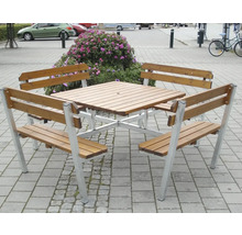Trädgårdsbord med fyra bänkar av trä och metall på en stenlagd yta