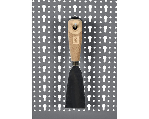 Spackelspade med trähandtag på en perforerad vägg