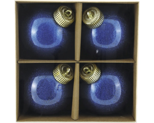 Fyra blå julgranskulor med gyllene hängare i en kartong.