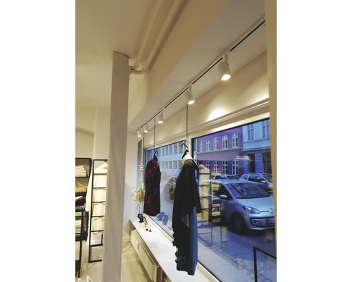 Interiör av en butik med kläder hängande på en skena med spotlights