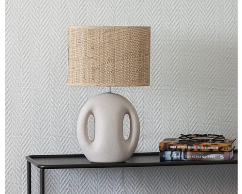 Bordslampa med lampskärm av bast på ett svart bord