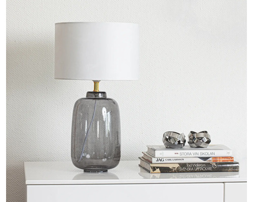 Dekorativ bordslampa i glas med lampskärm på ett bord