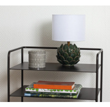 Dekorativ hylla med lampa, burk och böcker