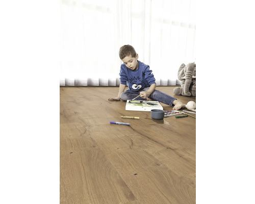 Barn målar på ett trägolv. I bakgrunden finns en gosedjurs elefant.