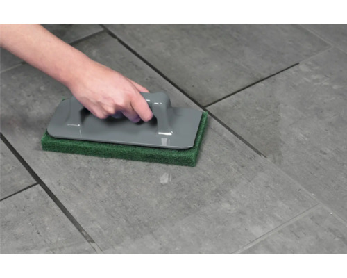 Hand som använder fogborste på kakel