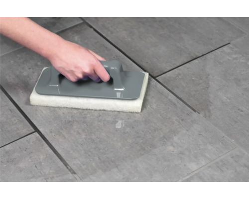 Hand använder kakelsvampbräda för rengöring av kakel