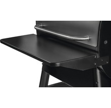 Detaljvy av en svart grill med hylla och silverfärgat handtag