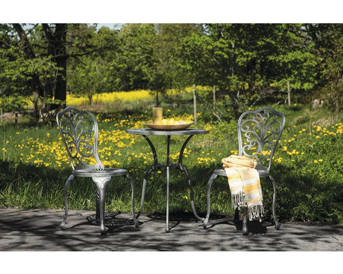 Trädgårdsscen med trädgårdsbord och två trädgårdsstolar utomhus