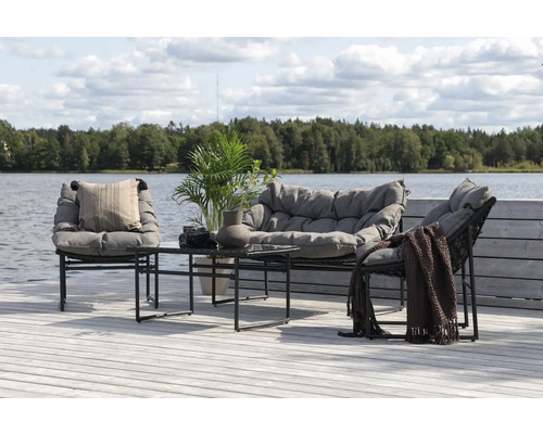 Trädgårdsmöbelset med soffa, stolar och bord på en träterrass vid sjön