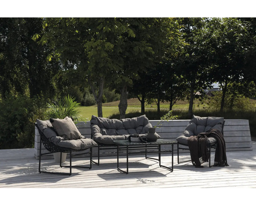 Trädgårdsmöbelset med loungestolar, soffa och bord på en träterrass framför träd