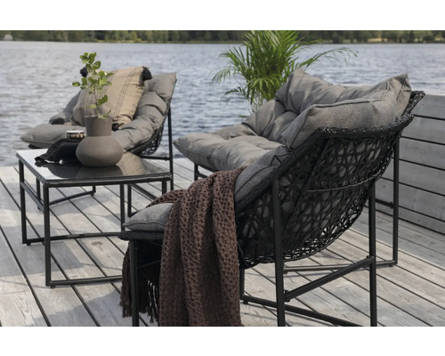 Trädgårdsmöbelset med två fåtöljer och ett bord på en terrass vid sjön