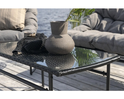 Trädgårdsscen med rottingbord med glasskiva, dekorativ vas och sittmöbler i bakgrunden