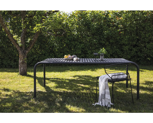 Trädgårdsscen med matbord, stol och dekorationer i grönskan