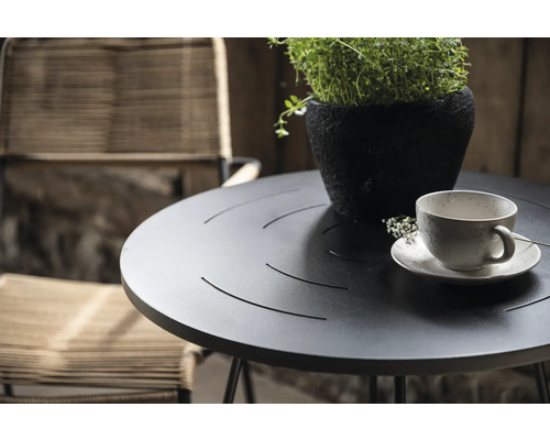 Trädgårdsscen med runt bord, växt i kruka och kaffekopp