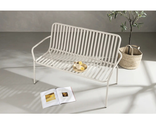 Metallbänk med bok och dryck i trädgården