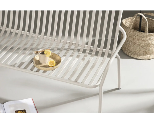 Detaljbild av en vit trädgårdssoffa med citron och korg