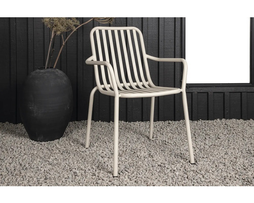 Metallfåtölj bredvid en vas på grusgolv