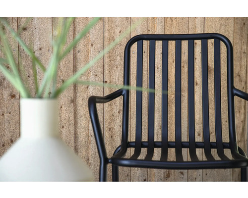 Svart metallfåtölj bredvid en vas