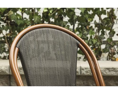 Detaljvy av en stol med ryggstöd av rottingflätning och brun ram