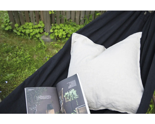 Hängmatta med kudde och tidning i trädgården