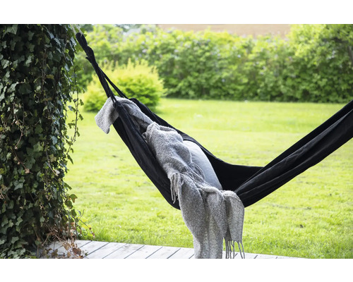 Svart hängmatta med filt och kudde i trädgården
