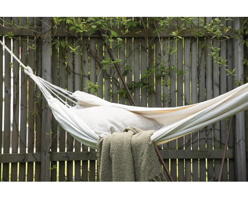 Vit hängmatta med kudde och filt i trädgården