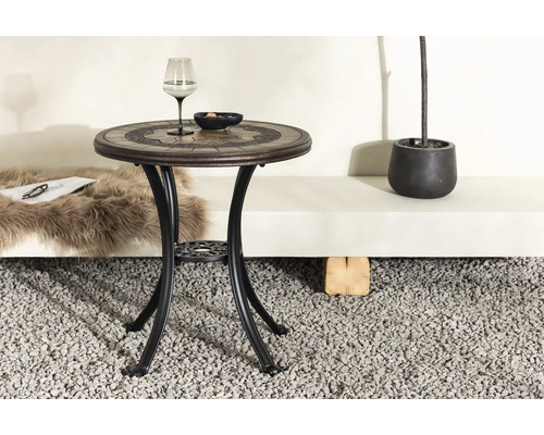 Trädgårdsbord med mosaikplatta, glas och skål på grus