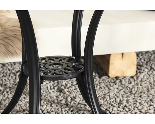 Detaljvy av underredet på ett runt trädgårdsbord av metall med dekorativt mönster