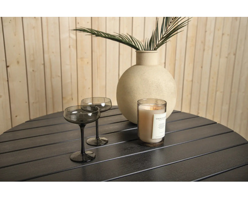 Två glas, ett ljus och en vas med en växt på ett bord
