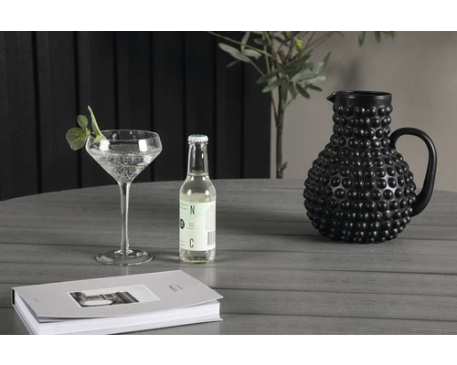 Stilleben med dricksglas, dricksflaska och keramikkanna på ett bord.