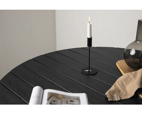 Detalj av ett runt trädgårdsbord med ljusstake, vas, träfat, tygservett och tidskrift