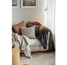 Dekorativa kuddar och plädar med ribbad textur arrangerade på en soffa