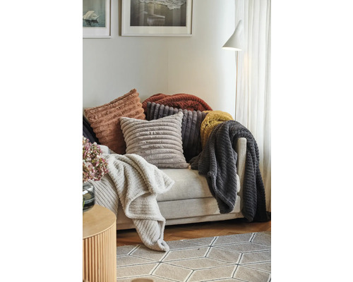 Dekorativa kuddar och plädar med ribbad textur arrangerade på en soffa