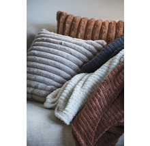 Olika kuddar och filtar med ribbad struktur på en soffa