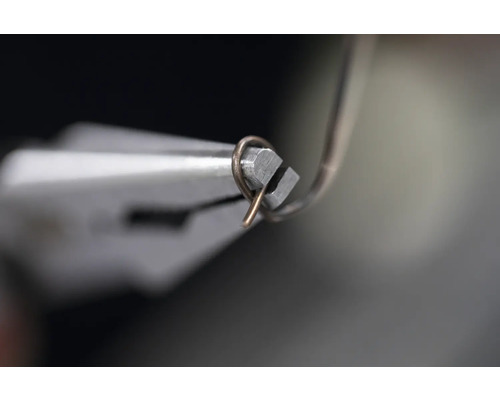 En tång böjer en tråd.