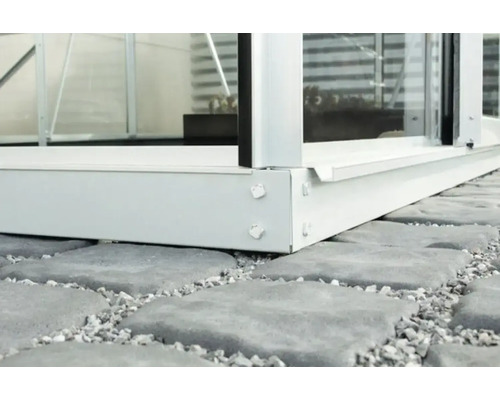 Detaljvy av en växthusgrund av aluminium på gatsten.