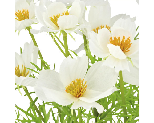 Närbild av konstgjorda vita blommor med gula accenter och gröna stjälkar.