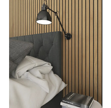 Sovrumsscen med säng, vägglampa och stapel med böcker