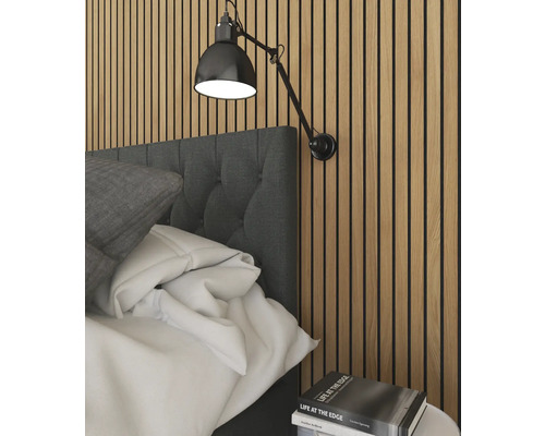 Sovrumsscen med säng, vägglampa och stapel med böcker