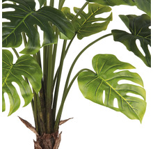 Närbild av en konstgjord Monstera-växt med gröna blad.