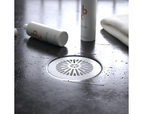 Golvbrunn i badrum med hygienprodukter och handduk