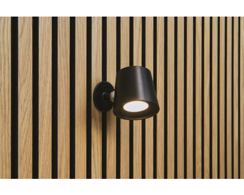 Svart vägglampa på en vägg med träpaneler