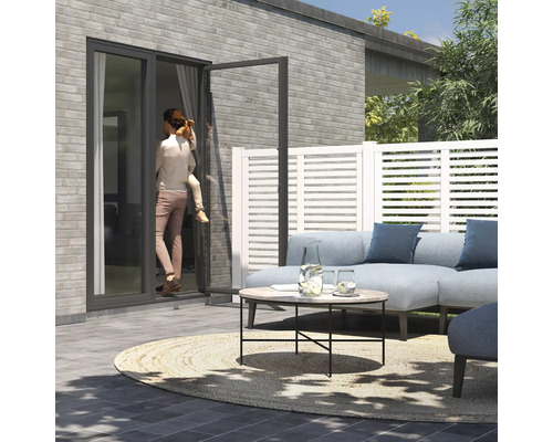 Terrass med loungemöbler, staket och en kvinna med ett barn vid en altandörr