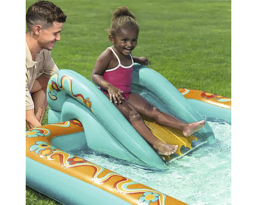 Barn åker på en uppblåsbar vattenrutschkana i en pool