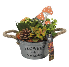 Blomsterarrangemang i en metallhink med texten Blommor och trädgård, tillsammans med dekorativa svampar och en tallkotte.