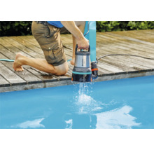 En person använder en Gardena dräneringspump vid poolen.