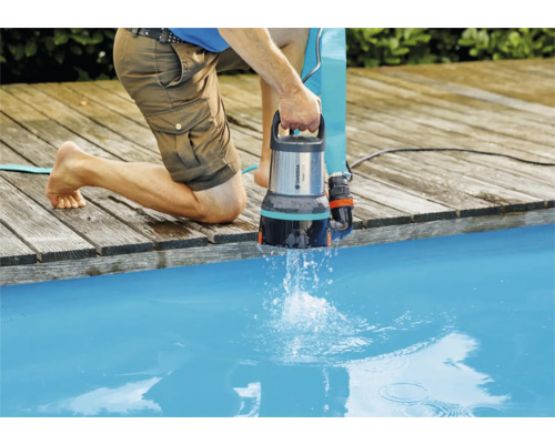 En person använder en Gardena dräneringspump vid poolen.
