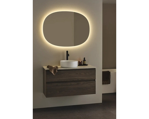 Badrum med tvättställsskåp, tvättställsskål och belyst spegel