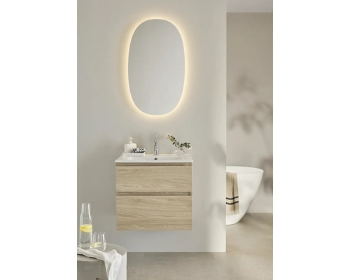 Modernt badrum med upplyst spegel, tvättställsskåp med lådor och badkar.