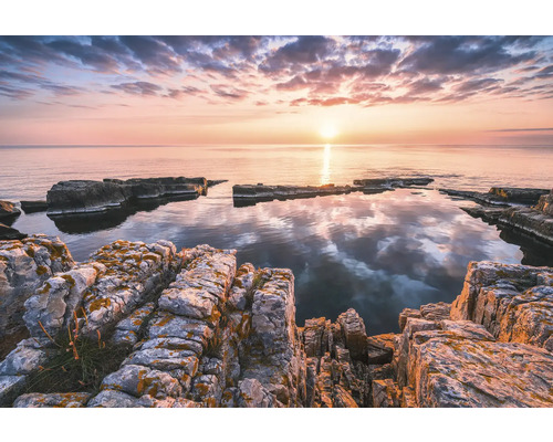 Klippigt kustlandskap i soluppgång med lugnt vatten